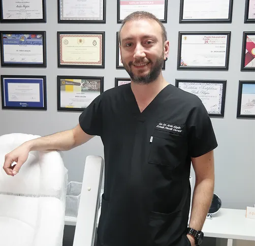 Op. Dr. Arda Akgün in his clinic, with his framed qualifications on the wall behind him