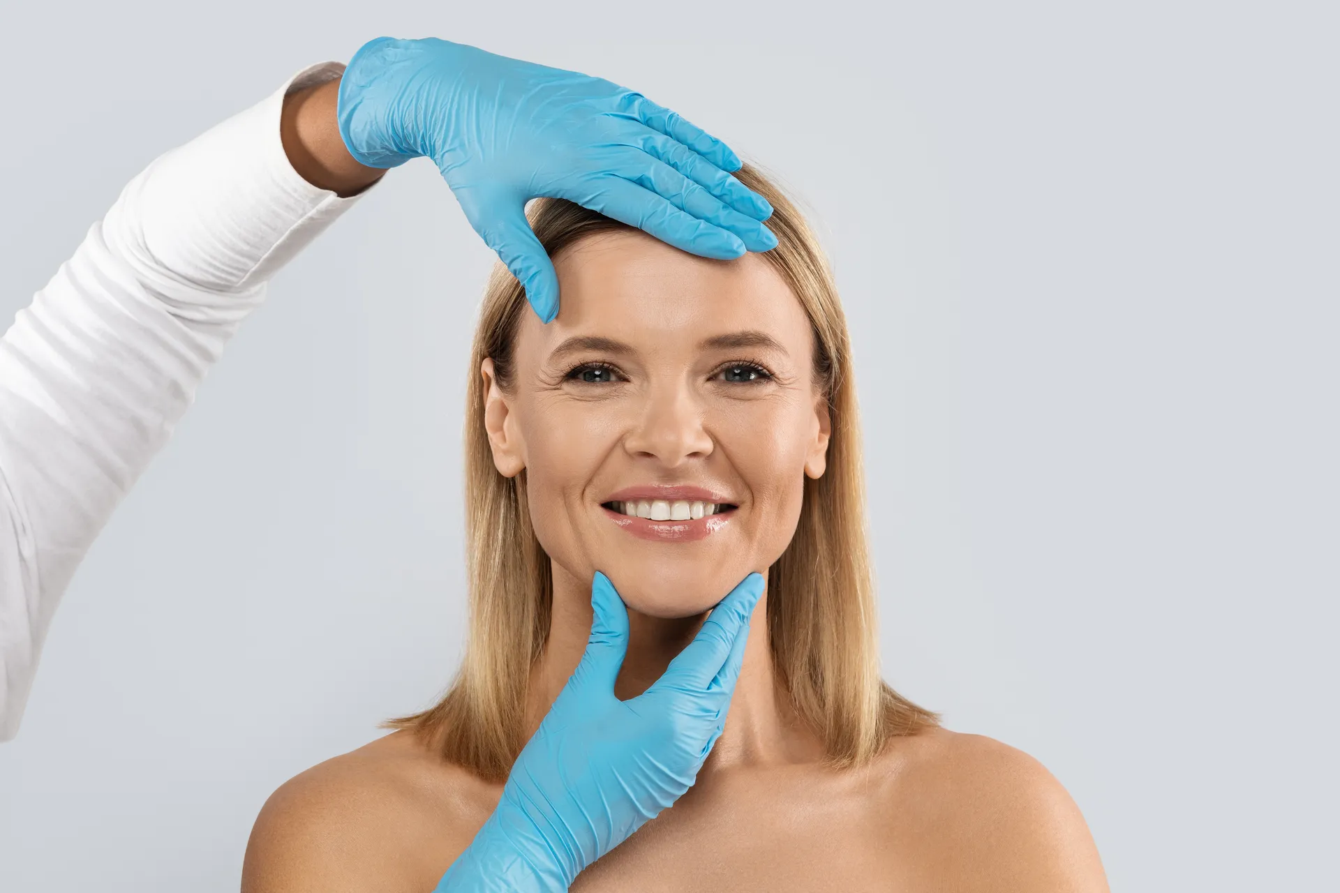 Un chirurgien ganté évalue les proportions du visage d’une patiente lors d’une consultation