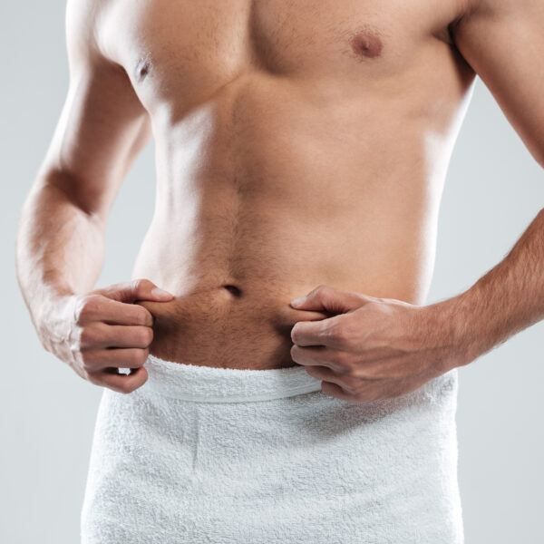 Cropped image of young man dressed in towel standing isolated over grey background.